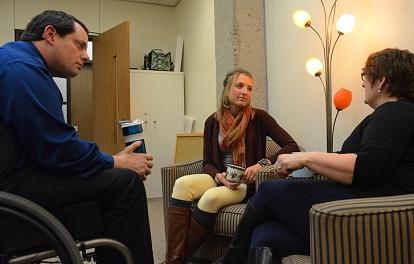 a male and two females having a discussion in a room